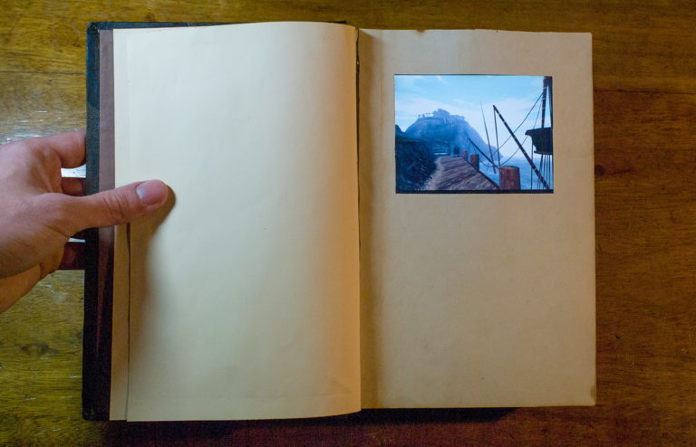 An open book with a small computer screen inside it showing a view on a dock